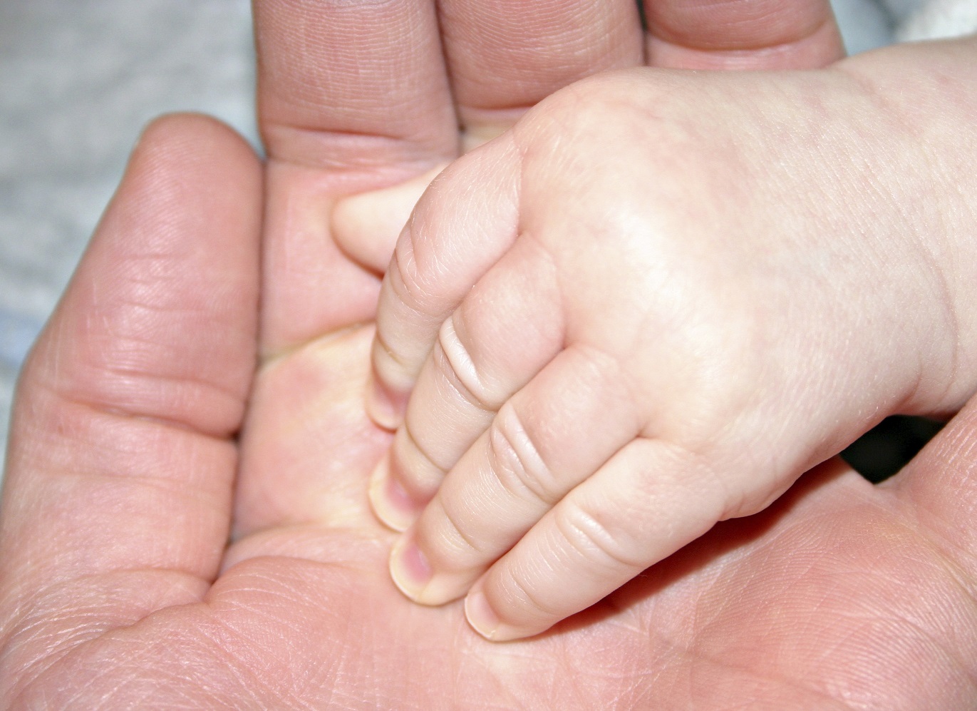 An infant hand in an adult hand
