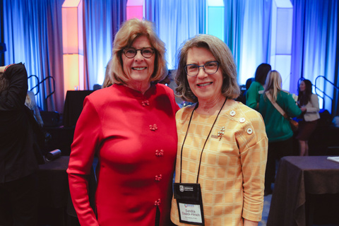 Two women stand together and smile at camera