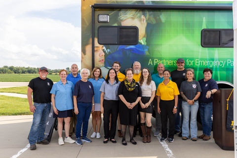 A group of about 15 people stands outside for a photo.