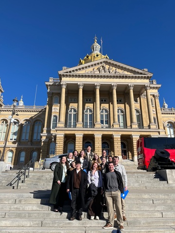 group stands on steps in front of Iowa capitol building