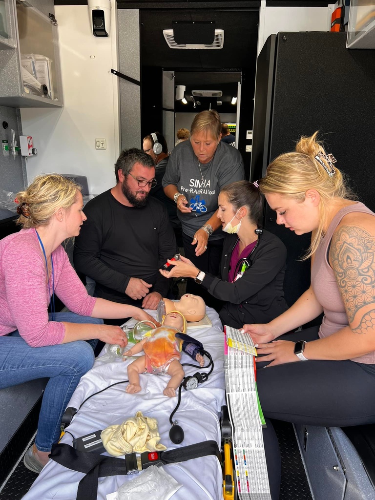 Five people surround an infant patient simulator in the back of a truck.