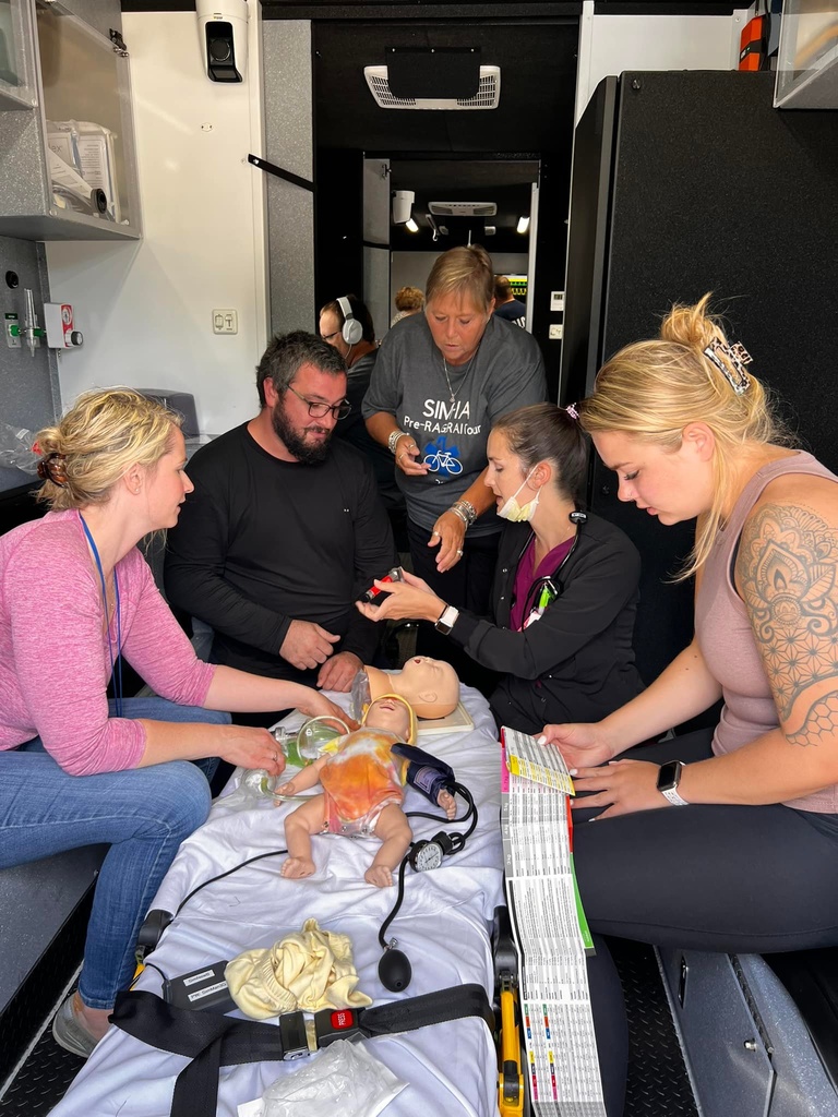 Five people surround an infant patient simulator in the back of a truck. 