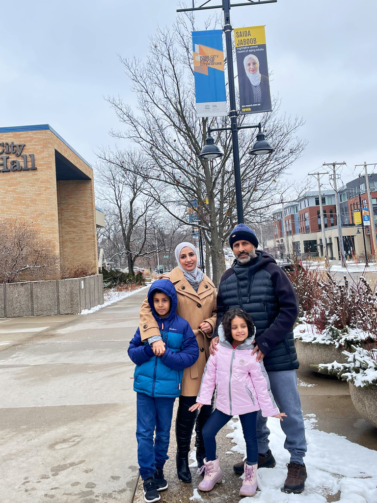 Saida Jaboob and her family in front of her Dare to Discover banner in downtown Iowa City.