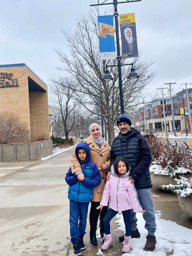 Saida Jaboob and her family in front of her Dare to Discover banner in downtown Iowa City. 