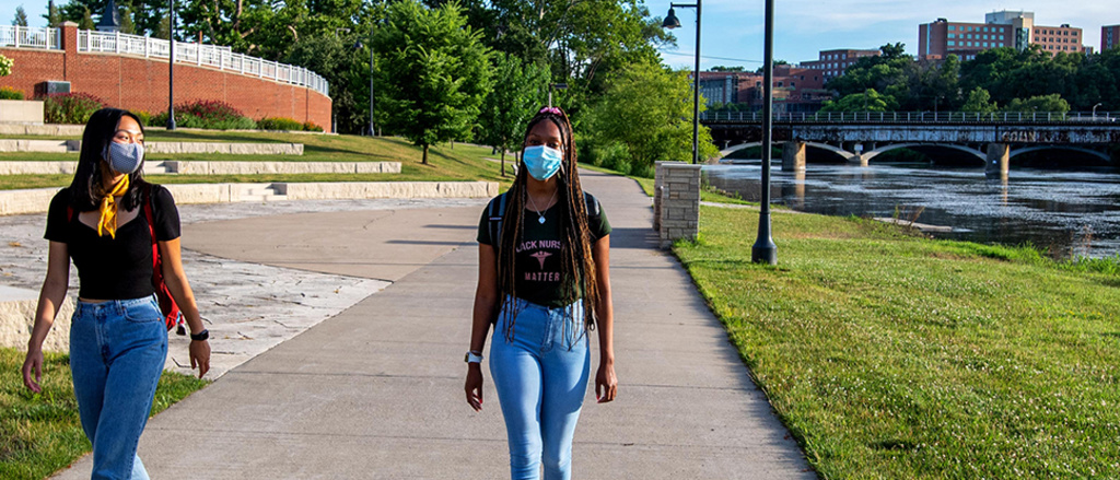 Two students walking by the Iowa river