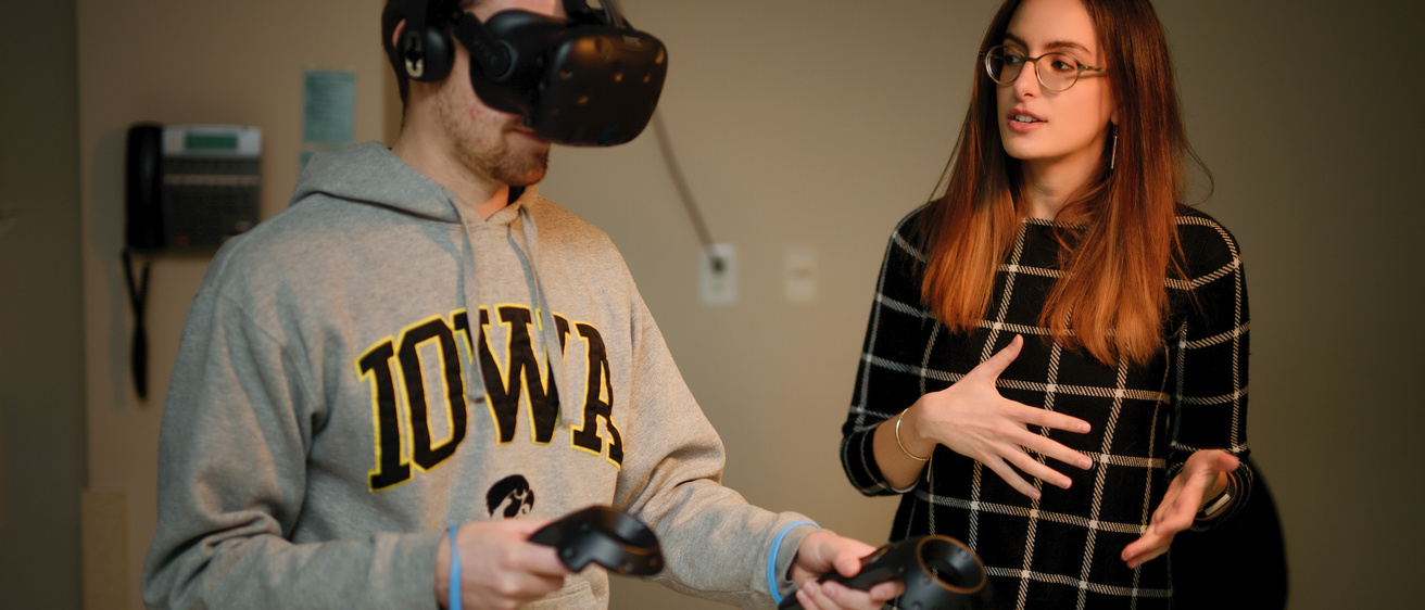 A PhD student working with another student on virtual reality device