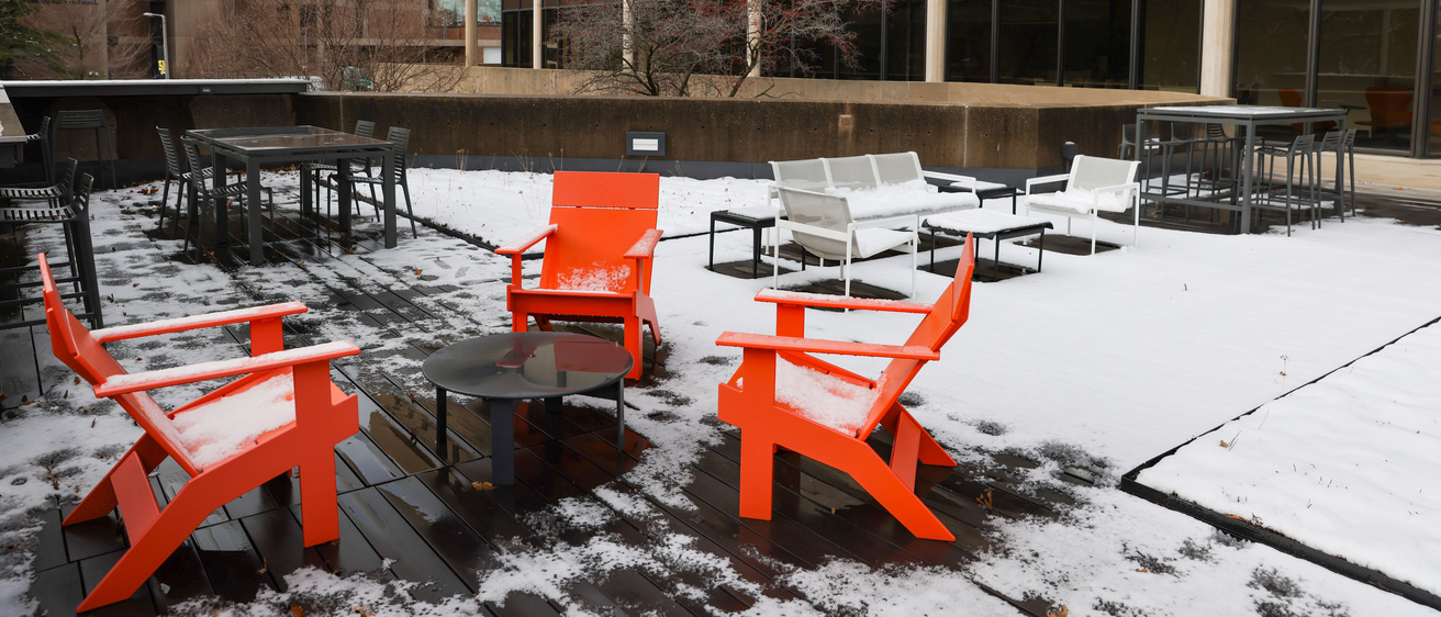 Three orange chairs and snow on terrace of nursing building