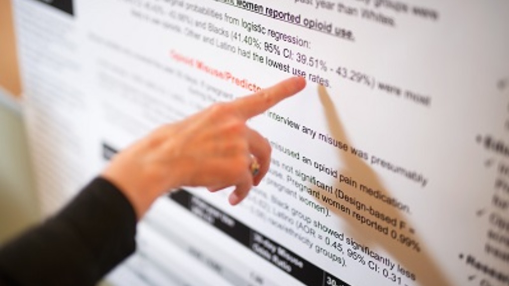 A finger pointing at a research poster