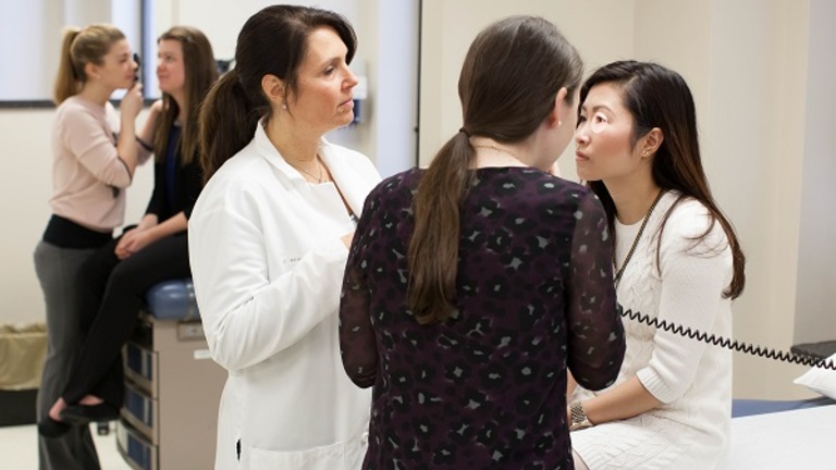 Prof. Dirks with a student practitioner, who is examining a patient